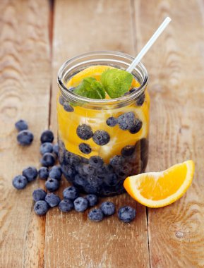 Çilek ve limonla dolu bir kavanoz. Tahta bir yüzey üzerinde kamışla.