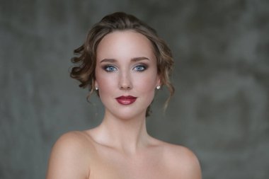 Gri arka planda makyajlı hoş bir genç kadın.