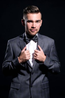 şeritli bir arka plan üzerinde koyu takım elbise ve kravat takan yakışıklı adam sakallı bir poz