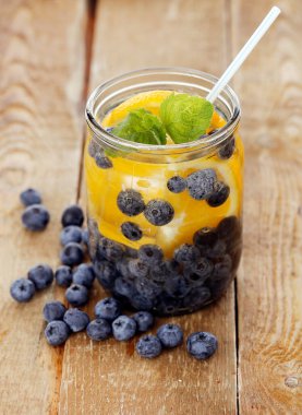 Çilek ve limonla dolu bir kavanoz. Tahta bir yüzey üzerinde kamışla.