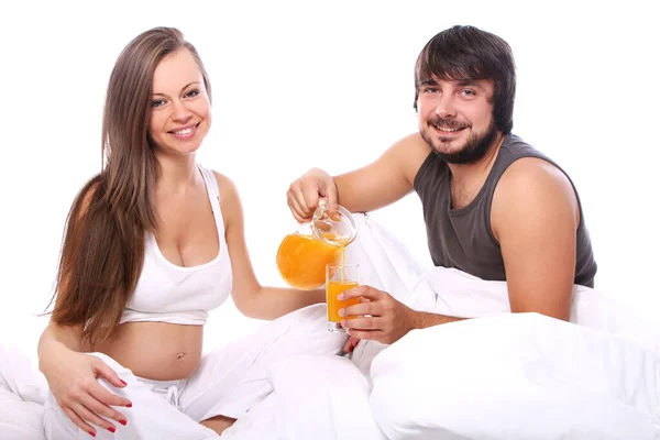 躺在床上喝橙汁的年轻夫妇 — 图库照片