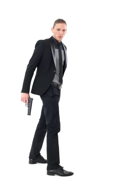 黒のスーツのハンサムな男と白い背景の上にポーズをとるピストル — ストック写真