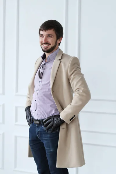 ハンサムな男でコートにポーズの白い壁の背景 — ストック写真