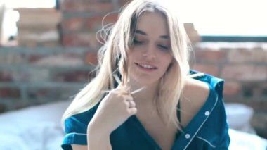 Evdeki yatakta kameraya poz veren bir kadın. 