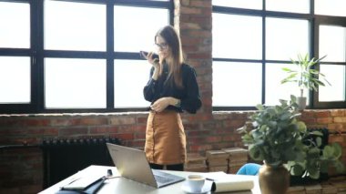 İş kadını ofiste akıllı telefondan konuşuyor.