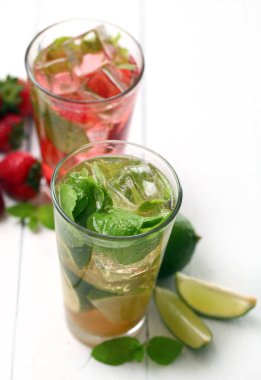 Beyaz ahşap bir masada taze çilek ve naneli mojito.