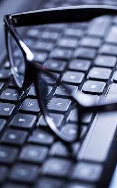 Üzerinde gözlük olan parlak bir dizüstü bilgisayarın yakın plan fotoğrafı.