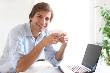 Ofiste poz veren mavi gömlekli yakışıklı bir genç.