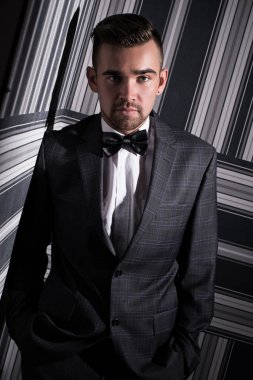 Çizgili arka planda poz veren takım elbiseli yakışıklı bir adamın portresi.