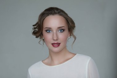 Gri arka planda makyajlı hoş bir genç kadın.