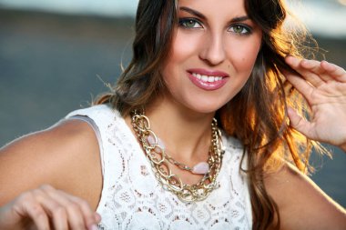 Gökyüzü arka planında poz veren kahverengi saçlı güzel bir kızın portresi.