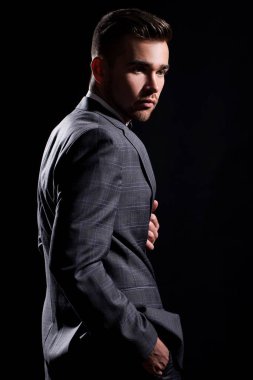 şeritli bir arka plan üzerinde koyu takım elbise ve kravat takan yakışıklı adam sakallı bir poz