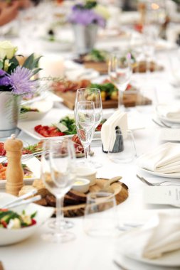 Bir kutlamada, içinde çiçekler ve bir sürü farklı yiyecek olan büyük bir yemek masası.