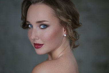 Gri arka planda makyajlı hoş bir genç kadın.