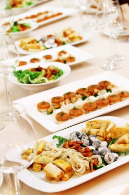 Restoran servisi ve atıştırmalıklarla dolu bir ziyafet masası.