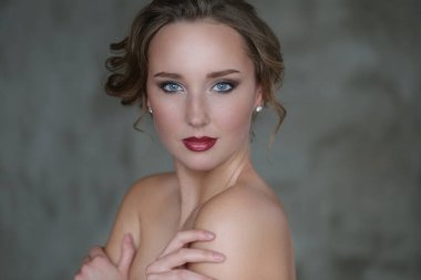 Gri arka planda makyajlı hoş bir genç kadın.