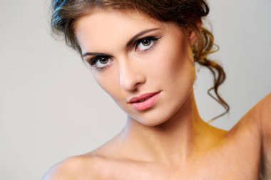 kıvırcık saçlı ve hafif bir arka plan üzerinde poz çıplak omuzlarına güzel esmer bir kadın portresi