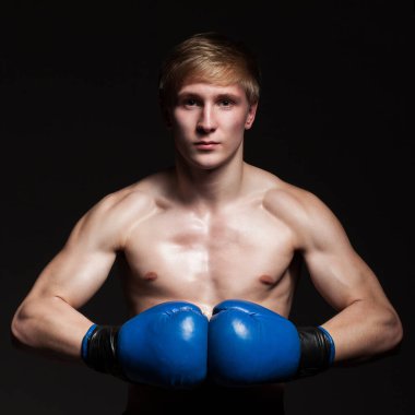 Siyah arka planda mavi eldivenli yakışıklı bir boksör.