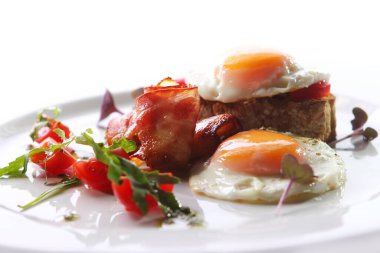 Çırpılmış yumurta, domuz pastırması ve yeşil bir tabakta servis edilir.