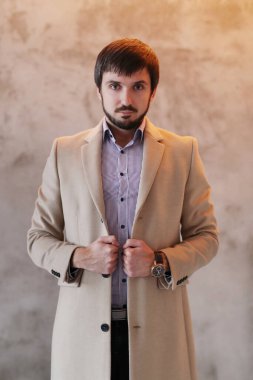 Palto giyen yakışıklı adamın stüdyo portresi.