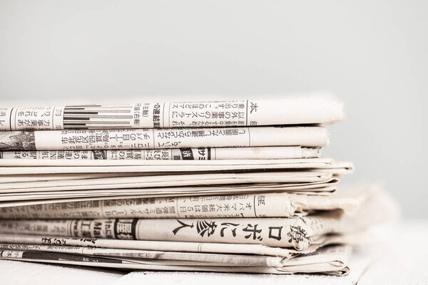 Pile of black and white newspapers on a wooden table