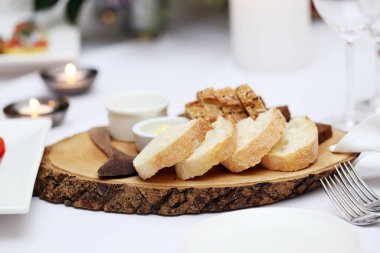 Ekşi kremalı iki farklı ekmek ve tahta bir tabakta duran tahta bir kaşık.