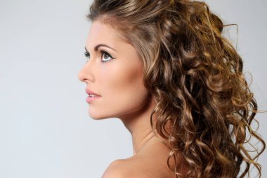 kıvırcık saçlı ve hafif bir arka plan üzerinde poz çıplak omuzlarına güzel esmer bir kadın portresi