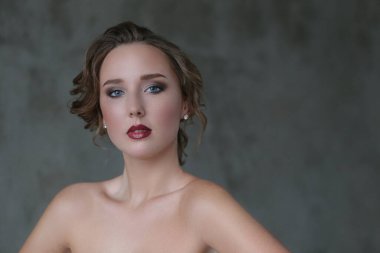 Gri arka planda makyajlı hoş bir genç kadın.