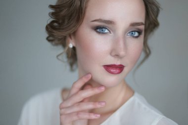 Gri arka planda makyajlı hoş bir genç kadın.