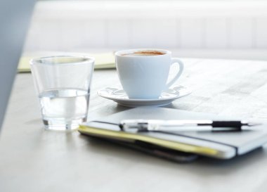 İş yeri. Kahve fincanı ve bir bardak su masanın üstünde.