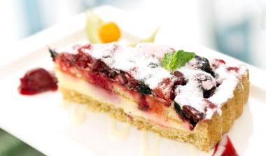 Lezzetli katmanlı meyveli kek ve beyaz tabakta diğer meyveler.