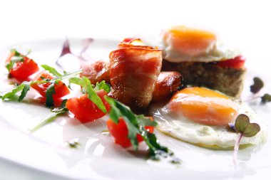 Çırpılmış yumurta, domuz pastırması ve yeşil bir tabakta servis edilir.