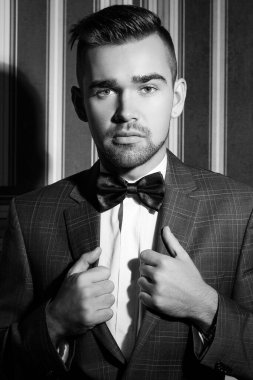 Çizgili arka planda poz veren takım elbiseli yakışıklı bir adamın portresi.