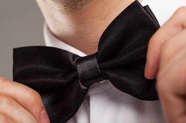 Bir erkeğin elleri takım elbisedeki papyona dokunur