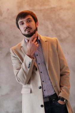 Palto giyen yakışıklı adamın stüdyo portresi.