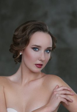 Gri arka planda makyajlı hoş bir genç kadın.