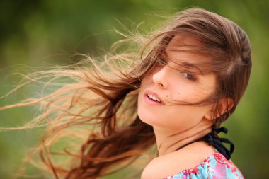 Rüzgarlı saçlarıyla gülümseyen genç bir kadının portresi. 