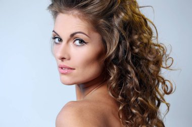 kıvırcık saçlı ve hafif bir arka plan üzerinde poz çıplak omuzlarına güzel esmer bir kadın portresi