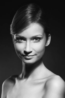 Güzel bir kadının siyah beyaz portresi. Arka planda çıplak omuzlarıyla poz veriyor.