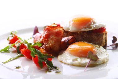 Çırpılmış yumurta, domuz pastırması ve yeşil bir tabakta servis edilir.