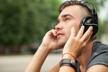 Sokağın ortasında otururken onun kulaklık müzik dinlediği yakışıklı bir adam portresi