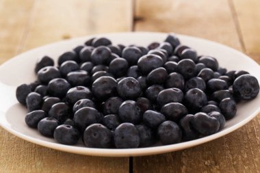 Ahşap bir yüzey üzerinde bir tabak yaban mersini