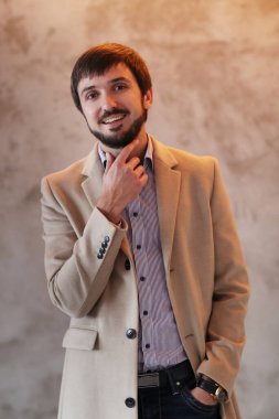 Palto giyen yakışıklı adamın stüdyo portresi.