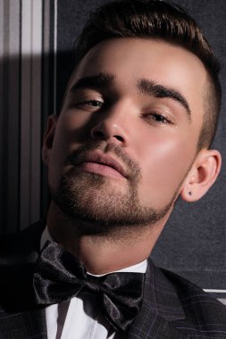 Çizgili arka planda poz veren takım elbiseli yakışıklı bir adamın portresi.