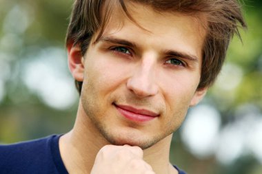 Parkta poz veren yakışıklı genç adamın portresi.