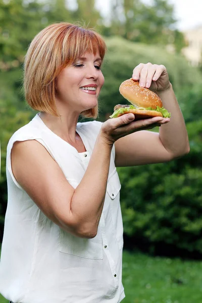 Retrato Uma Mulher Atraente Que Está Comendo Hambúrguer Parque — Fotografia de Stock