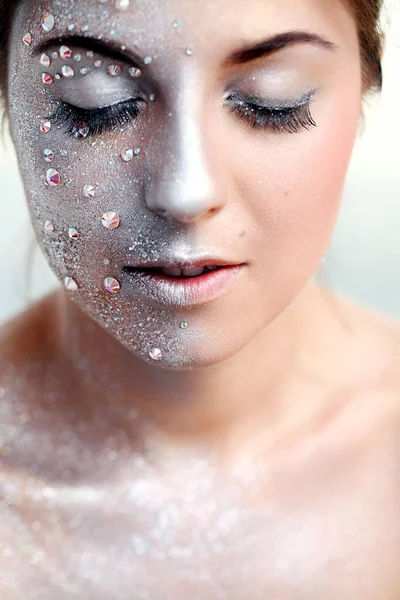 Beyaz bir arka plan üzerinde gümüş beden sanatı ile güzel bir kızın portresi