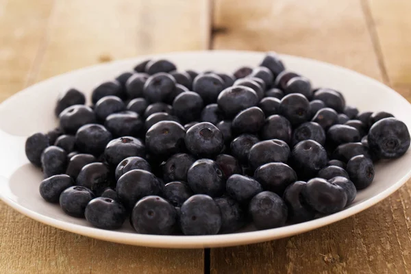 Ahşap bir yüzey üzerinde bir tabak yaban mersini