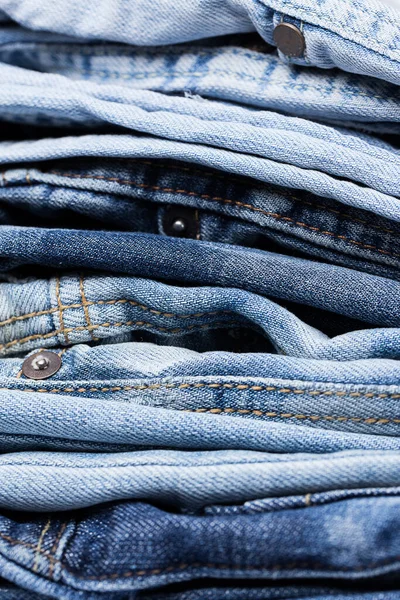 A closeup picture of a pile of various jeans