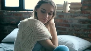 Evdeki yatakta kameraya poz veren bir kadın. 